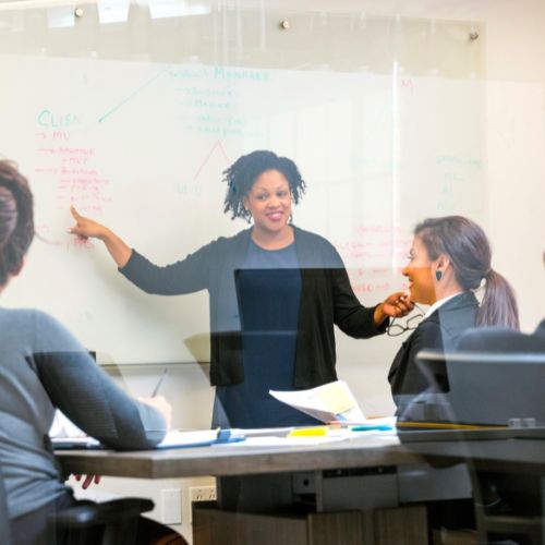 Woman standing in front of a white board in a meeting